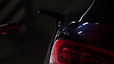 Kadın akşam otoparkta elektrikli arabayı şarj ediyor.