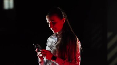 Kadın gece vakti otoparkta elektrikli arabayı şarj ediyor.