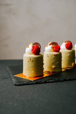 Taze ahududu ve parlak jöleli kremalı hamur işleri içeren zarif bir tatlı gösterisi.