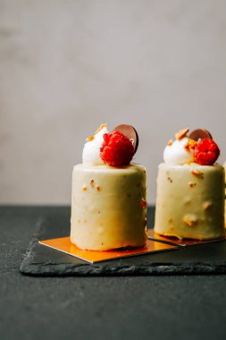 Tatlı vitrininde krema ve ahududu kaplı lezzetli küçük kekler.