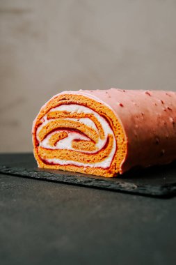 Modern bir ortamda canlı krema ve pasta katmanlarıyla lezzetli bir tatlı rulosu.