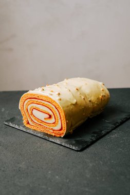 Minimalist bir ortamda siyah bir levhada gösterilen renkli katmanlı pasta.