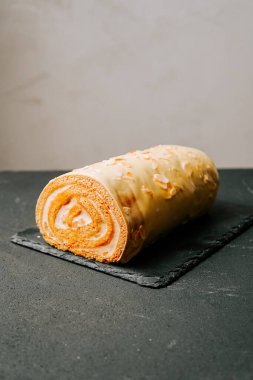 Koyu bir tahtada kremalı pasta sergileniyor.