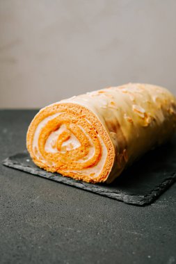 Lezzetli portakallı kek rulosu bir pastanenin siyah tahtasında sergileniyor.