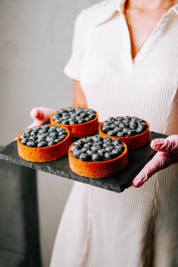 Pasta şefi modern mutfak ortamında lezzetli yaban mersinli turtalar sunuyor.