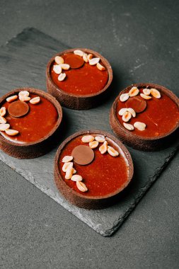 Fıstıklı lezzetli çikolatalı tart. Koyu bir tabakta servis ediliyor.