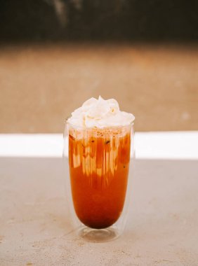 Bardakta servis edilen yenilenebilir içecek, üzerinde krema ve parlak bir ayar.