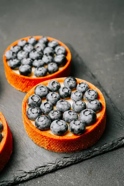 Lezzetli yaban mersinli turtalar. Koyu bir tabakta ayarlanmış. Tatlı sanatını sergiliyorlar.