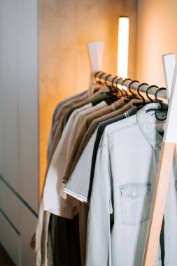 Modern bir perakende mağazasında çeşitli tişörtlerin sergilendiği şık bir elbise rafı.