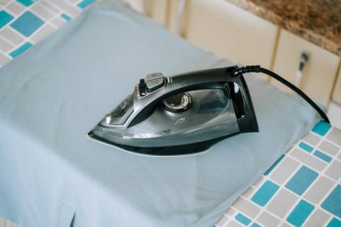 Çamaşır odasındaki ütü masasının üzerinde duran mavi kumaş.