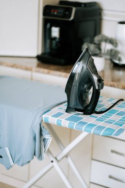 Ütü masasına ütülenmiş ütü, mutfak düzeninde gömlek.