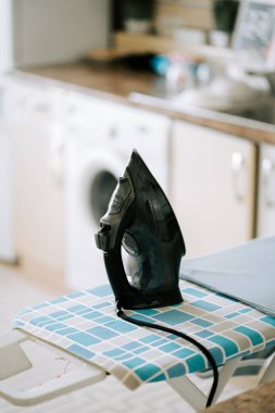 Kara demir bir çamaşır odasındaki desenli ütü masasında dinleniyor.