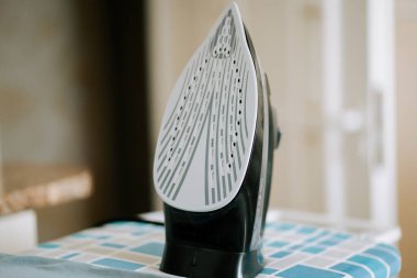 Demir, çamaşır odasındaki ütü masasında dik duruyor.