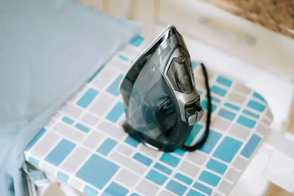 Demir mavi ve gri geometrik ütü masasında sabit duruyor