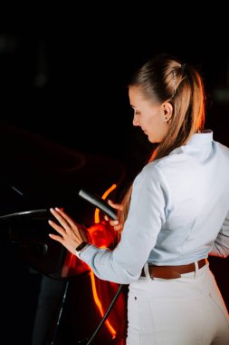 Kadınlar geceleri modern yeraltı otoparkında elektrikli araç yüklüyorlar.