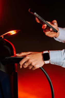 Geceleri renkli neon ışıkların altında elektrikli araba yükleyen bir kadın.