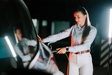 Kadın geceleri elektrikli arabayı parlak neon ışıklarıyla dolduruyor.