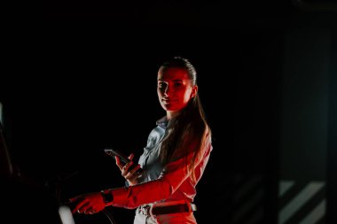 İş kadını, aynı anda birden fazla telefon kullanırken yeraltı istasyonunda elektrikli araba şarj ediyor.