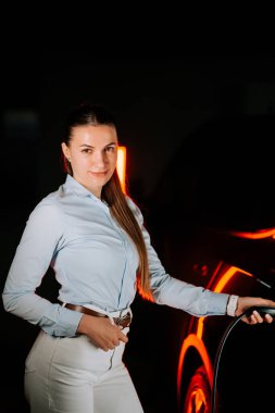 İş kadını gün içinde yeraltı otoparkında elektrikli araç şarj ediyor.