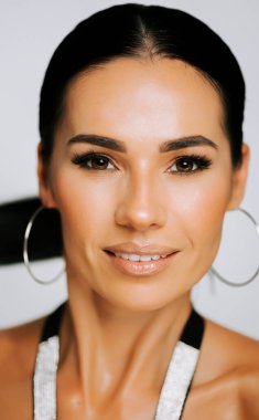 Parlak gülüşlü bir kadın stüdyo ortamında yakın plan bir portre için zarif poz verir.