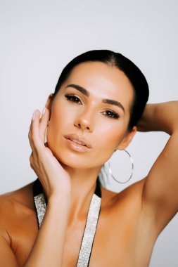 Model zarif bir poz veriyor. Stüdyo ortamında güzellik ve moda sergiliyor.