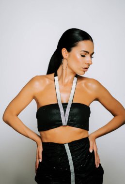 Bir modelin moda portresi, sade bir arka planda kendine güvenen şık bir kıyafetle poz veriyor.