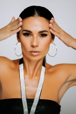 Zarif bir kadın kendine güvenen şık bir elbiseyle basit bir arkaplana karşı poz veriyor.