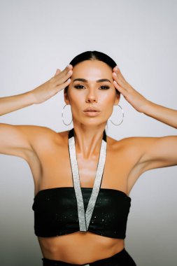 Stüdyo ortamında çarpıcı bir aksesuarla poz veren şık bir kadın.