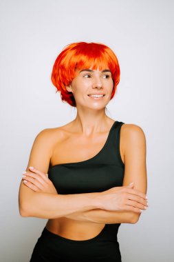 Canlı turuncu saçlı bir model, sade bir arkaplana karşı güvenle poz verir.