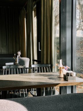 Şık bir restoran ortamında yumuşak doğal ışık alan rahat bir yemek salonu.