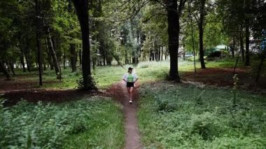 Yeşillik ve ağaçlarla çevrili huzurlu bir orman yolunda koşuyor.