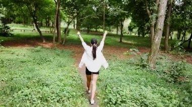 Güneşli bir günde yemyeşil bir parkta doğa yürüyüşünün tadını çıkarıyorum.