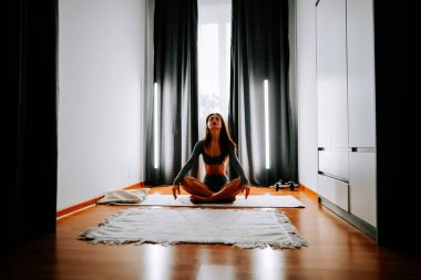 Sabahları rahat evinde yoga ve meditasyon yapan genç bir kadın.