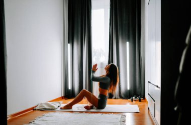 Sabahları huzurlu bir evde yoga yapan genç bir kadın.