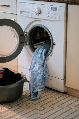 Çamaşırhanede çamaşır makinesi ve çamaşır sepetiyle çamaşır yıkamak.