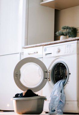 Çağdaş bir çamaşır odasında çamaşır makinesiyle kirli çamaşırları yıkamak.