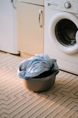 Çamaşır odasında çamaşır makinesi ve sepetle kirli çamaşırları yıkamak.