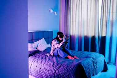 Genç bir kadın sıcak, neon ışıklı bir odada video oyunu oynamaktan zevk alıyor.