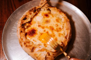 Lezzetli Adjarian Khachapuri sıcak servis edildi. Sıcak bir restoranın tavanında yağlı bir yumurta ile.