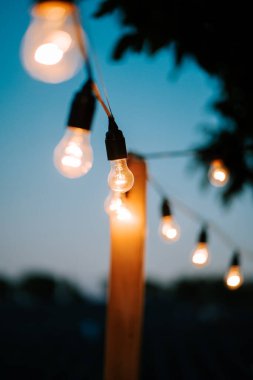 Sicim ışıklarının sıcacık parıltısı alacakaranlıkta rahat bir açık alanı aydınlatıyor.