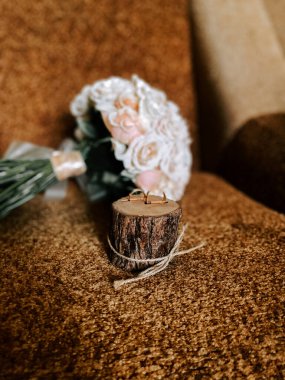 Alyanslar kırsal ahşap odunların üzerine yerleştirilmiş zarif bir buket çiçeğin yanına.