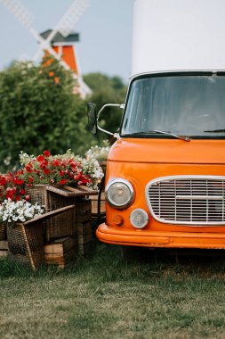 Kırsal kesimde canlı çiçek aranjmanlarının yanına park edilmiş klasik turuncu kamyon.