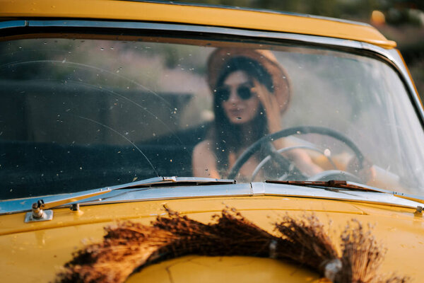 Young woman driving a vintage yellow car on a sunny day in a relaxed atmosphere