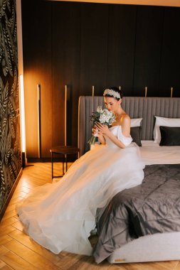 Modern otel odasında zarif dekorlu ve hafif ışıklandırmalı gelinlik hazırlığı.