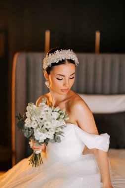 Zarif gelin, hoş bir çiçek buketiyle sıcacık bir yerde düğün gününe hazırlanıyor.