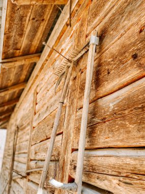 Yıpranmış ahşap aletler kırsal alanda eski bir ahır duvarında dinleniyor.