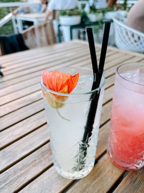 Açık bir kafedeki ahşap bir masada çiçekle süslenmiş taze bir kokteyl.