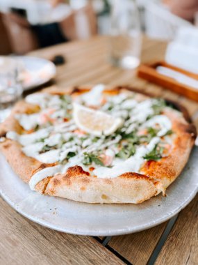 Lezzetli taze pişmiş pizza, yanında soslar ve masada bir dilim limon.