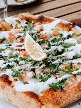 Somon ve roka soslu lezzetli pizza. Açık hava restoranında servis ediliyor.
