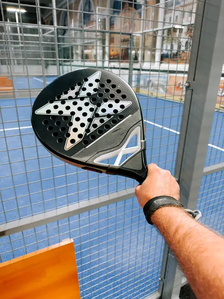 Padel raketi, öğleden sonra bir şehir spor tesisinde maç başlatmaya hazır bir oyuncunun elinde.
